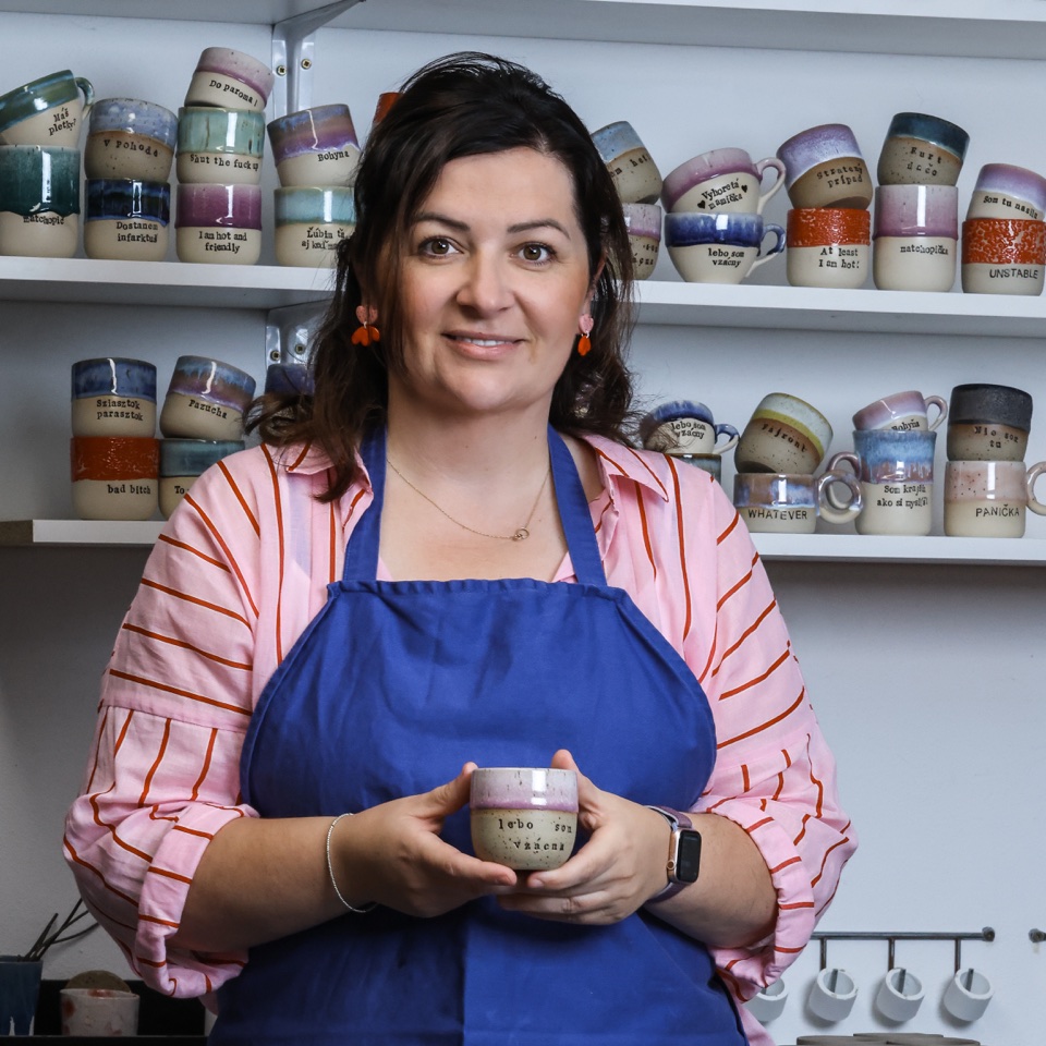 Ceramic maker holding a handmade cup in her studio – photography by Filip Labanc for No Smile Needed