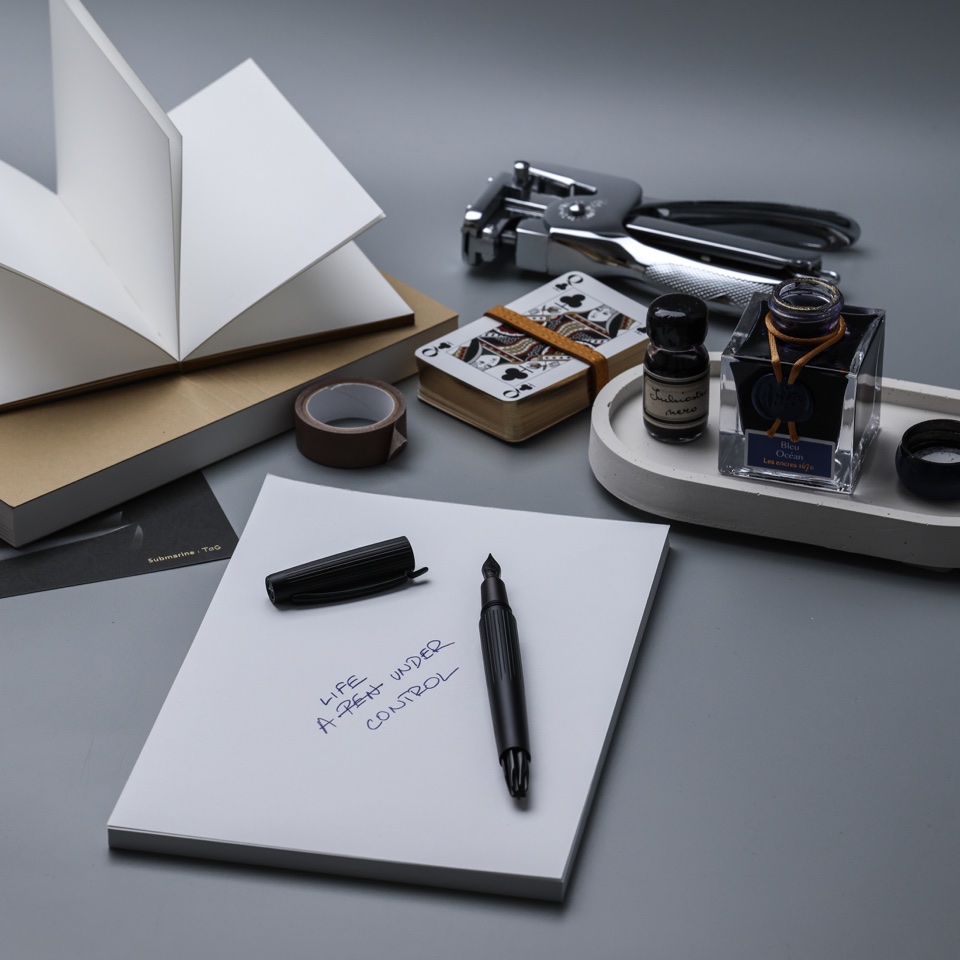 Fountain pen and ink bottles arranged with stationery on a desk – photography by Filip Labanc for No Smile Needed